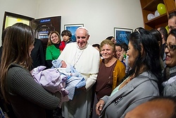 Pope Francis cradles an infant while visiting family in Varginha community of Rio de Janeiro